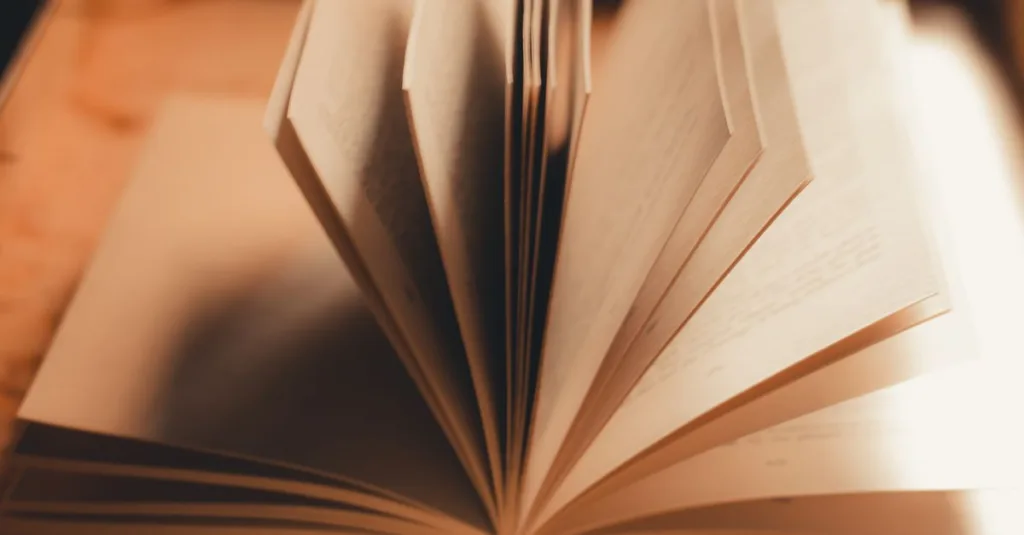 Jepretan dekat dari buku terbuka dengan halaman yang terbuka dalam cahaya hangat dan lembut.