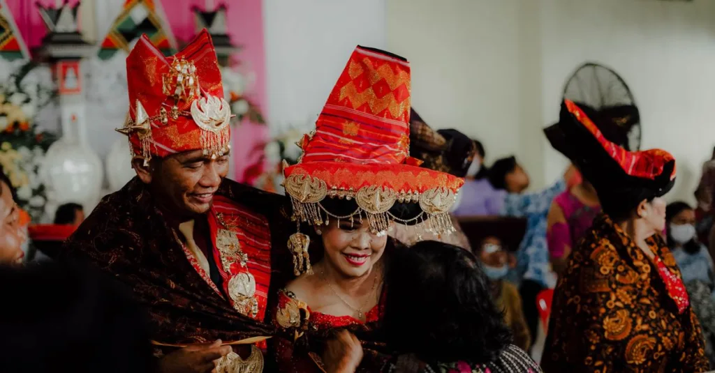 Momen bahagia selama pernikahan tradisional Indonesia dengan pakaian dan dekorasi budaya.