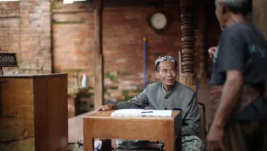 Dua pria terlibat dalam percakapan di lingkungan budaya di Kudus, Indonesia.