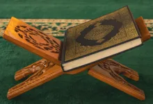 Sebuah Al-Qur'an terletak di atas podium kayu yang dipahat dengan indah di dalam masjid, menampilkan seni Islam.