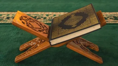 Sebuah Al-Qur'an terletak di atas podium kayu yang dipahat dengan indah di dalam masjid, menampilkan seni Islam.