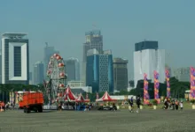 Karnaval kota dengan bianglala dan gedung pencakar langit di latar belakang, suasana perkotaan yang semarak.