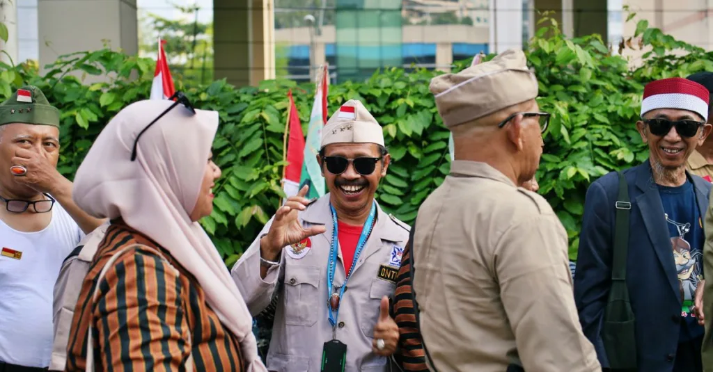 Sekelompok veteran Indonesia berseragam menikmati percakapan di luar ruangan, menunjukkan rasa persahabatan.