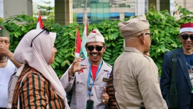 Sekelompok veteran Indonesia berseragam menikmati percakapan di luar ruangan, menunjukkan rasa persahabatan.
