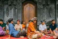 Sekelompok pria berpakaian tradisional duduk di luar pura Bali, asyik mengobrol.