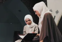 Dua wanita Muslim membaca Al-Qur'an di lingkungan masjid yang tenang di Bandung, Indonesia.