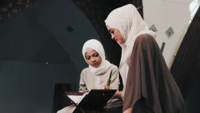 Dua wanita Muslim membaca Al-Qur'an di lingkungan masjid yang tenang di Bandung, Indonesia.