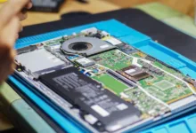 Tampilan dekat laptop yang sedang diperbaiki dengan komponen dan peralatan yang terlihat.