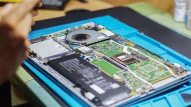 Tampilan dekat laptop yang sedang diperbaiki dengan komponen dan peralatan yang terlihat.