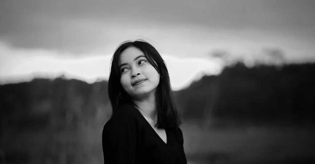 Potret hitam putih yang menawan dari seorang wanita muda yang melihat ke atas di luar ruangan.