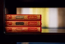 Tiga Quran dengan sampul yang ornamen dipajang di rak kayu di dalam masjid, menyoroti budaya Islam.