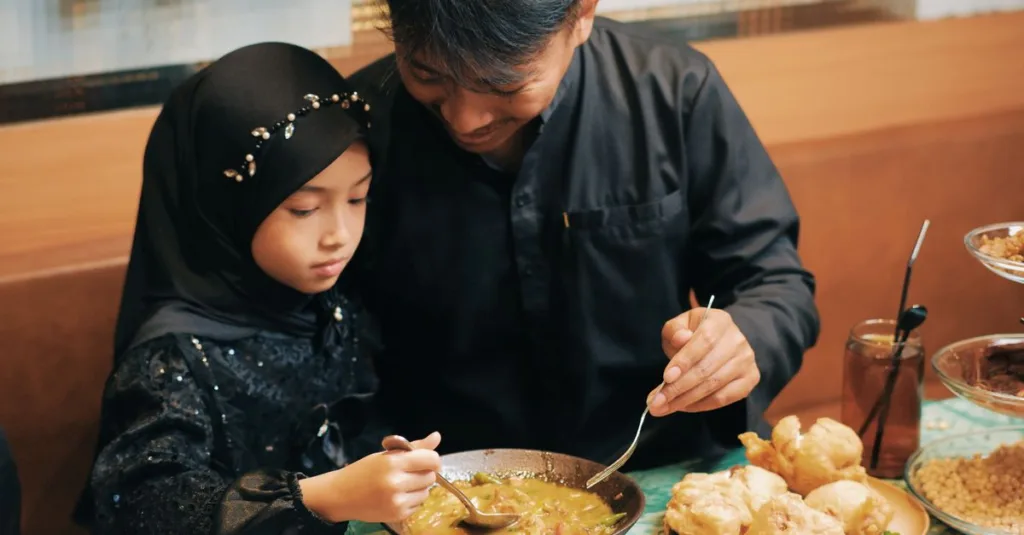 Ayah dan anak perempuan berbagi makanan tradisional, mengabadikan momen keluarga yang hangat di Indonesia.