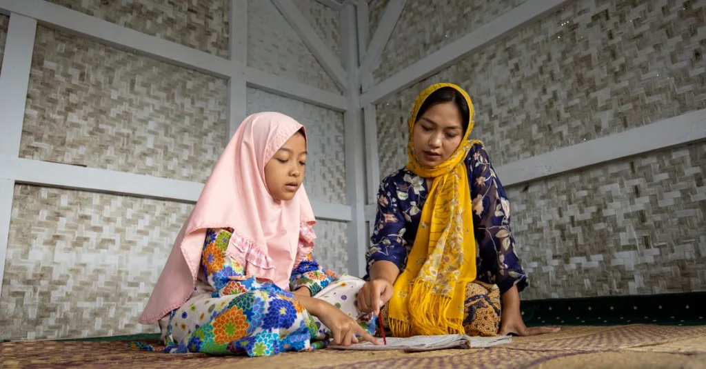 Seorang ibu dan anak perempuannya belajar Al-Quran bersama di rumah mereka di Bandung, Indonesia.