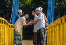 Laki-laki berpakaian tradisional saling menyapa dengan hangat di jembatan gantung di Jawa Barat, Indonesia.