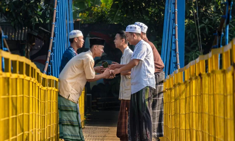 Laki-laki berpakaian tradisional saling menyapa dengan hangat di jembatan gantung di Jawa Barat, Indonesia.