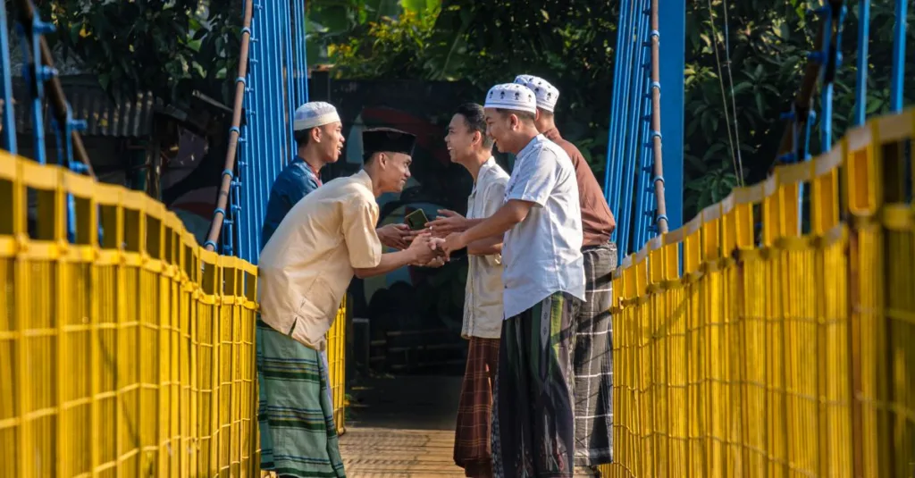 Laki-laki berpakaian tradisional saling menyapa dengan hangat di jembatan gantung di Jawa Barat, Indonesia.