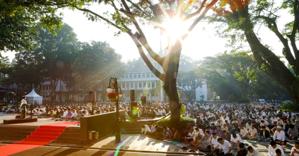 Pertemuan doa di luar ruangan yang diterangi sinar matahari di bawah pepohonan di Indonesia, mencerminkan persatuan dan spiritualitas.