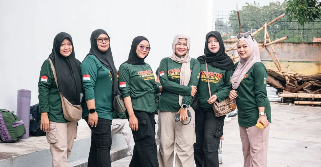 Enam wanita berpakaian hijau berkumpul untuk aktivitas pembentukan karakter di luar ruangan, menunjukkan kebersamaan dan persatuan.
