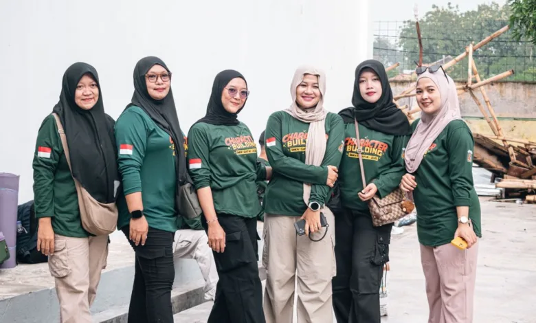 Enam wanita berpakaian hijau berkumpul untuk aktivitas pembentukan karakter di luar ruangan, menunjukkan kebersamaan dan persatuan.