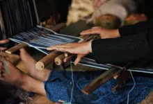 Tangan-tangan menenun kain di alat tenun tradisional di Banten, Indonesia.