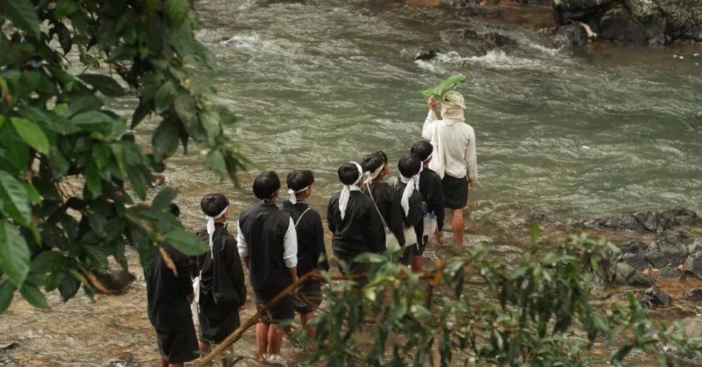 Ritual budaya di tepi sungai di Banten, Indonesia, yang menampilkan pakaian tradisional dan pertemuan komunitas.