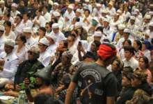 Sekumpulan besar orang mengenakan pakaian tradisional menghadiri upacara keagamaan di luar ruangan di Jawa Barat, Indonesia.