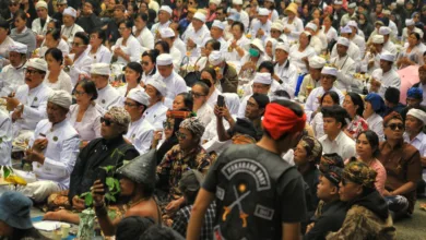 Sekumpulan besar orang mengenakan pakaian tradisional menghadiri upacara keagamaan di luar ruangan di Jawa Barat, Indonesia.