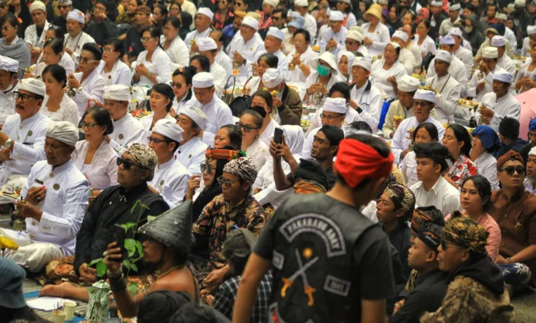 Sekumpulan besar orang mengenakan pakaian tradisional menghadiri upacara keagamaan di luar ruangan di Jawa Barat, Indonesia.