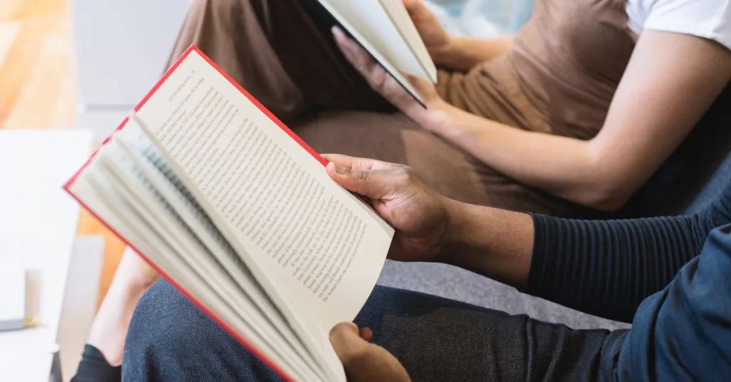 Dua mahasiswa membaca buku di dalam ruangan, fokus pada pembelajaran dan pengetahuan.