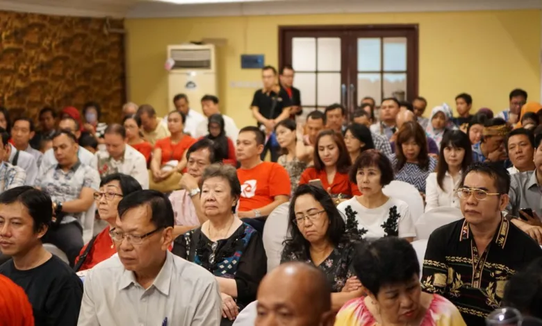 Sekelompok orang dewasa yang beragam menghadiri konferensi di sebuah pengaturan dalam ruangan di Indonesia.